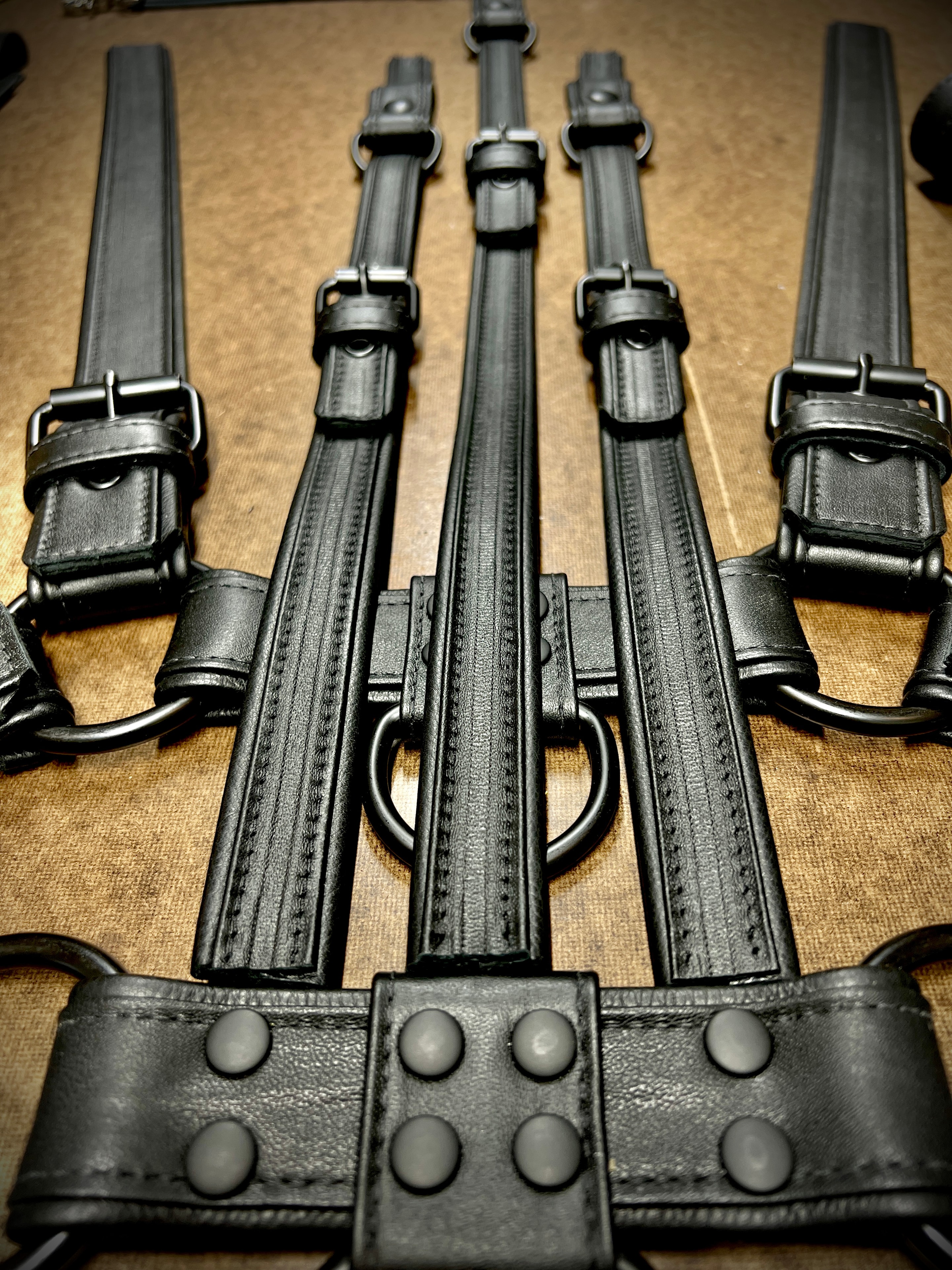 Black leather harness straps with buckles flat lay on kraft