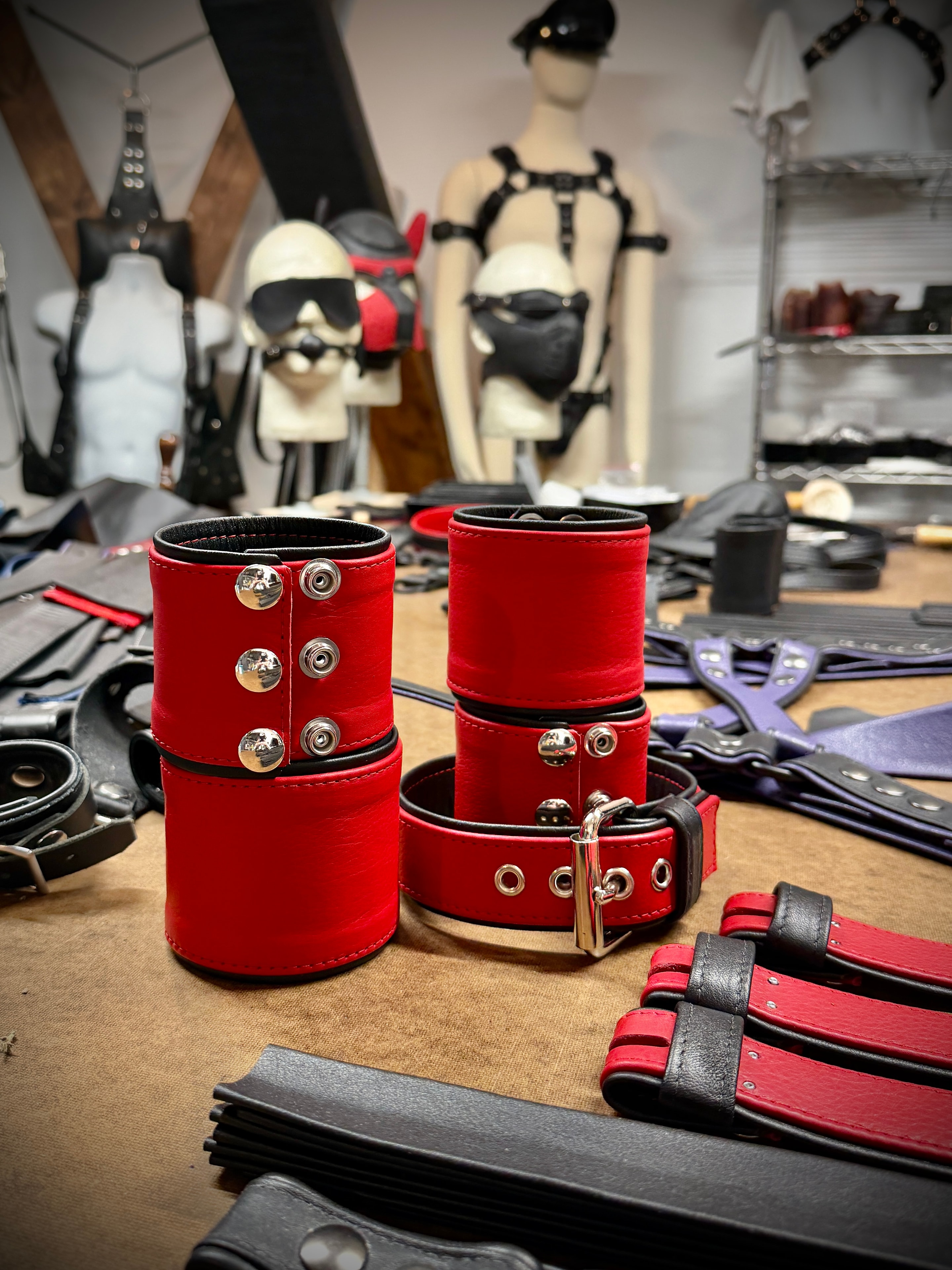 Red leather armbands and cuffs on workshop table