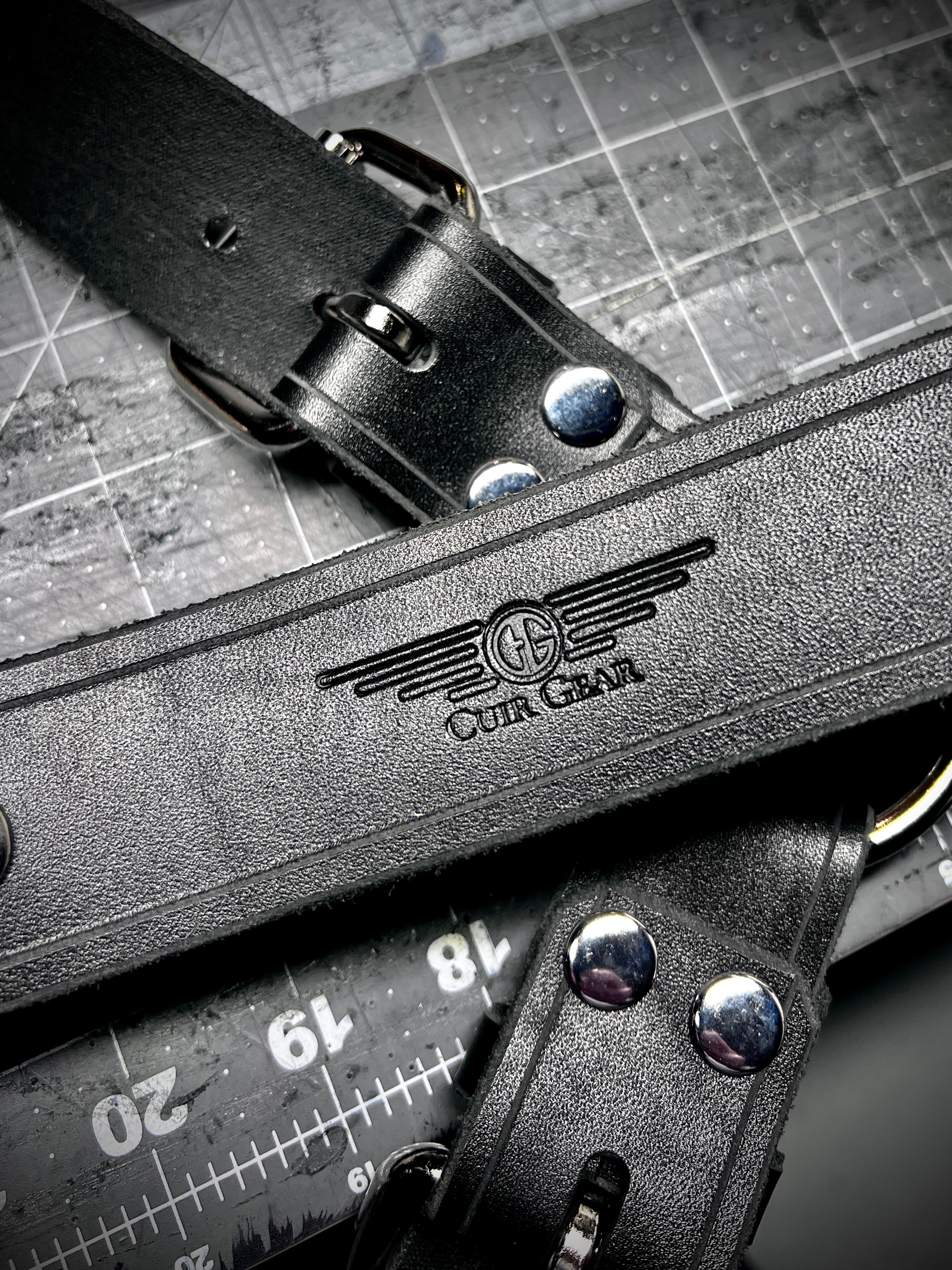 Cuir Gear logo stamped on black leather strap on cutting mat
