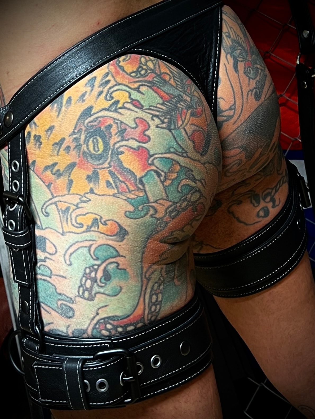 Tattooed thigh in black leather jockstrap colourful tattoos