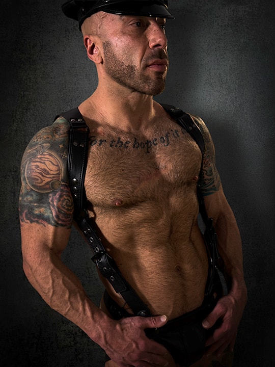Professional portrait tattooed man in leather cap dark studio